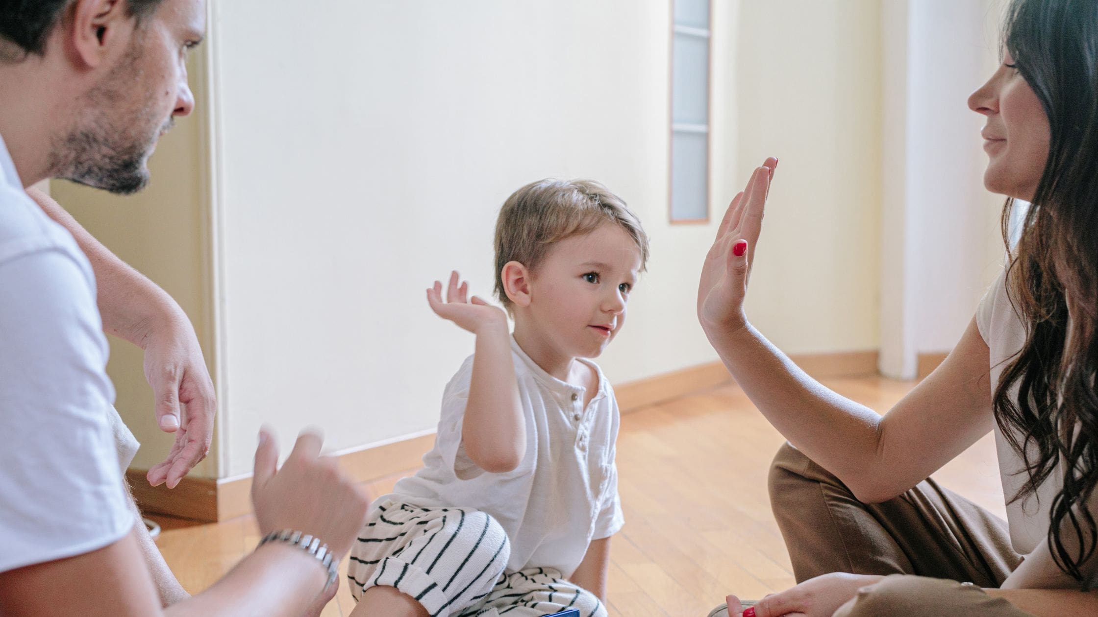 boy hifiving his parents. How To Raise Successful Kids Without Over-Parenting