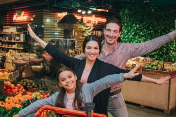 Playful Grocery Outing – A family poses with energetic expressions in a vibrant supermarket, adding fun and personality to an everyday errand, turning it into a memorable moment