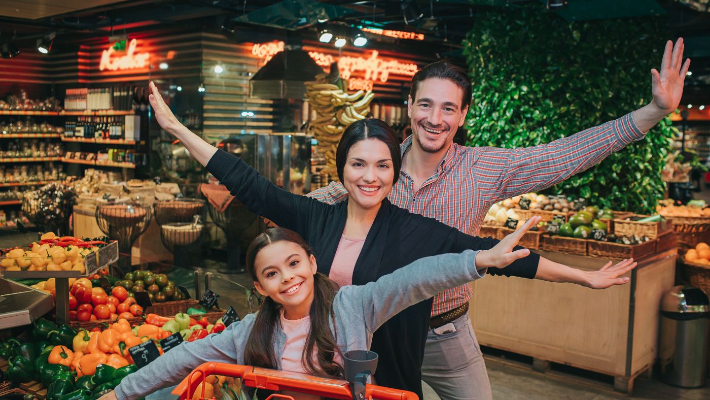 Playful Grocery Outing – A family poses with energetic expressions in a vibrant supermarket, adding fun and personality to an everyday errand, turning it into a memorable moment